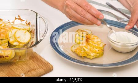 Courgettes cuites sur une assiette. Tranches de courgettes avec sel d'assaisonnement, poivre noir et fromage, servies avec de la crème aigre. Banque D'Images