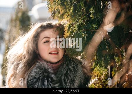 Une fille aux yeux bleus émotionnels soufflant de la neige dans ses mains. Hiver gelé. Banque D'Images