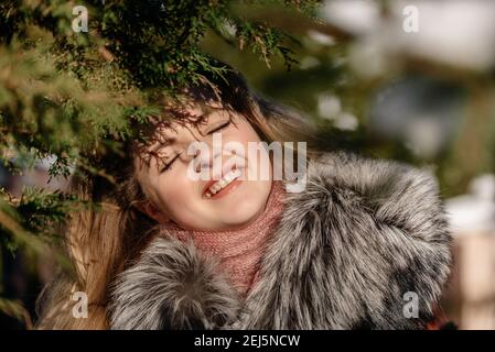 Une fille aux yeux bleus émotionnels soufflant de la neige dans ses mains. Hiver gelé. Banque D'Images