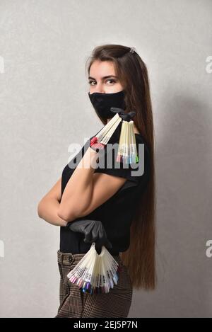 Une jeune femme manucuriste dans un masque facial montre une palette de couleurs vernis à ongles Banque D'Images