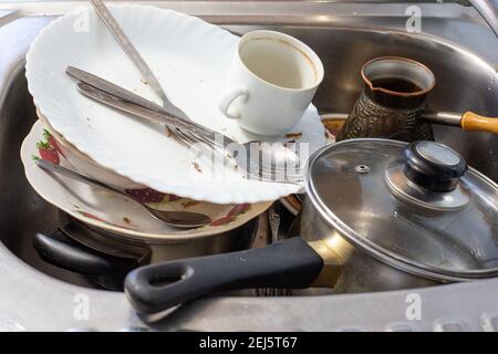 les plats sales après le dîner se trouvent dans l'évier, nettoyant la table dans la cuisine Banque D'Images