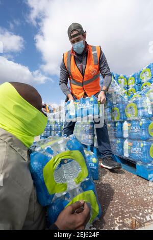 Oak Hill, TX USA 21 février 2021 : des volontaires transmettent des cas d'eau en bouteille à des habitants désespérés de l'ouest du comté de Travis, au Texas, hors de l'eau du robinet pendant plusieurs jours en raison de la tempête de neige dévastatrice du Texas la semaine dernière. Les conducteurs n'ont été autorisés qu'un seul cas par voiture après que certains aient attendu trois heures en file d'attente. Crédit : Bob Daemmrich/Alay Live News Banque D'Images