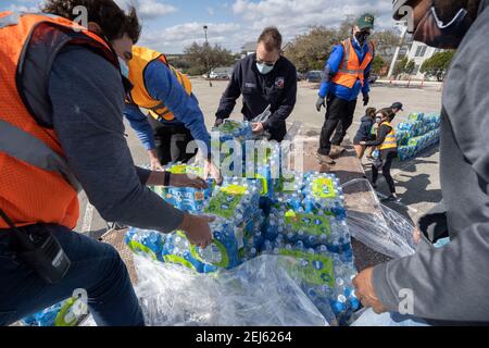 Oak Hill, TX USA 21 février 2021 : des volontaires transmettent des cas d'eau en bouteille à des habitants désespérés de l'ouest du comté de Travis, au Texas, hors de l'eau du robinet pendant plusieurs jours en raison de la tempête de neige dévastatrice du Texas la semaine dernière. Les conducteurs n'ont été autorisés qu'un seul cas par voiture après que certains aient attendu trois heures en file d'attente. Crédit : Bob Daemmrich/Alay Live News Banque D'Images