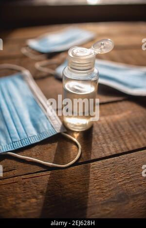 bouteille en plastique avec désinfectant pour les mains et masques jetables une table en bois Banque D'Images