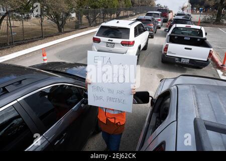 Oak Hill, TX USA 21 février 2021 : le volontaire Cherry Ward aide à organiser une longue gamme de véhicules sur un site de distribution d'eau en bouteille dans l'ouest du comté de Travis, au Texas. Les habitants de la région ont été sans eau courante pendant plusieurs jours en raison de la tempête de neige dévastatrice du Texas la semaine dernière. Les conducteurs n'ont été autorisés qu'une seule caisse par voiture après que certains ont attendu trois heures en sapin de ligne. Crédit : Bob Daemmrich/Alay Live News Banque D'Images