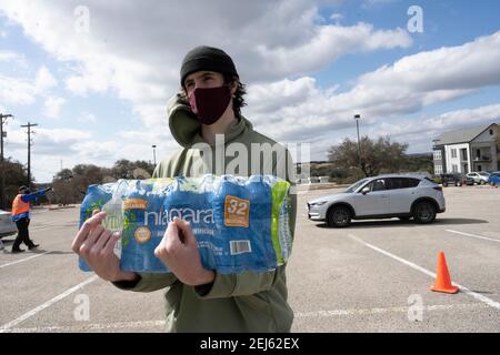 Oak Hill, TX USA 21 février 2021 : un volontaire aide à transmettre de l'eau aux habitants désespérés de l'ouest du comté de Travis, au Texas, à partir de l'eau du robinet pendant plusieurs jours en raison de la tempête de neige dévastatrice du Texas la semaine dernière. Les conducteurs n'ont été autorisés qu'un seul cas par voiture après que certains aient attendu trois heures en file d'attente. Crédit : Bob Daemmrich/Alay Live News Banque D'Images