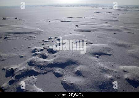 Vue aérienne en hiver du paysage gelé de la toundra arctique, recouvert de neige, près de Tuktoyaktuk, Territoires du Nord-Ouest, Canada. Banque D'Images