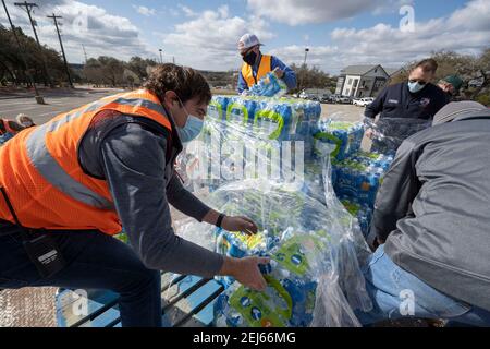 Oak Hill, Texas, États-Unis. 21 février 2021. Des bénévoles transmettent des cas d'eau embouteillée à des résidents désespérés de l'ouest du comté de Travis, au Texas, hors de l'eau du robinet pendant plusieurs jours en raison de la tempête de neige dévastatrice du Texas la semaine dernière. Les conducteurs n'ont reçu qu'un seul dossier par voiture après trois heures d'attente le 21 février 2021. Crédit : Bob Daemmrich/ZUMA Wire/Alay Live News Banque D'Images