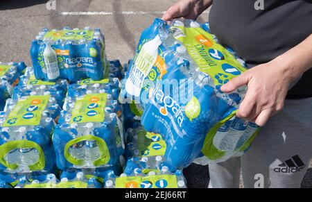 Oak Hill, Texas, États-Unis. 21 février 2021. Les bénévoles aident à transmettre l'eau à des résidents désespérés de l'ouest du comté de Travis, au Texas, à partir de l'eau du robinet pendant plusieurs jours en raison de la tempête de neige dévastatrice du Texas la semaine dernière. Les conducteurs n'ont reçu qu'un seul dossier par voiture après trois heures d'attente le 21 février 2021. Crédit : Bob Daemmrich/ZUMA Wire/Alay Live News Banque D'Images