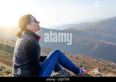 Une jeune fille touristique se trouve en haut de la montagne et admire le paysage ou se détend. Banque D'Images