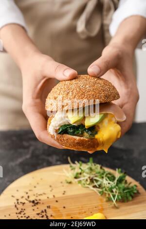 Femme tenant un savoureux hamburger avec des œufs florentins et des légumes frais, en gros plan Banque D'Images