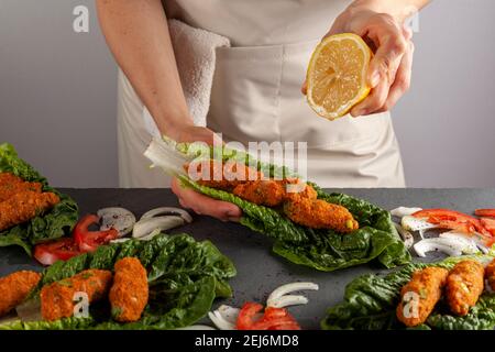 Plat turc traditionnel fait de bulgur cru et de lentilles connues comme mercimek koftesi (lentille pate) servi sur de la laitue verte avec des tranches d'oignon et de tomate Banque D'Images