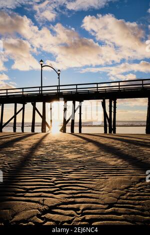 White Rock's Pier - avec des lanternes emblématiques est silhoueté contre un soleil couchant. Image prise d'une plage de sable très ondulée Banque D'Images