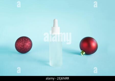 Huile de sérum avec collagène et peptide en flacon blanc transparent avec compte-gouttes sur fond bleu et boules rouges. Soins de la peau traitement de beauté médical Banque D'Images