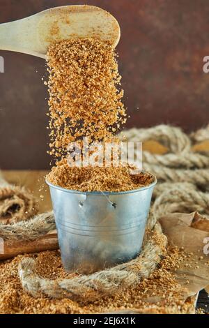 Le teff, une alternative à l'ancien grain sans gluten. Les gouttes de la cuillère en bois s'écouchent dans le seau. Banque D'Images