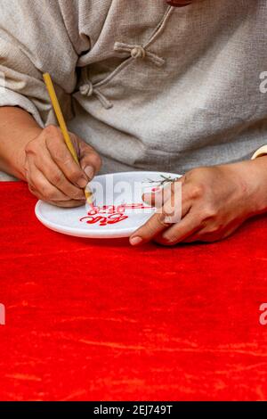 Photo verticale de la main humaine faisant l'écriture traditionnelle par calligraphie stylo à brosse Banque D'Images