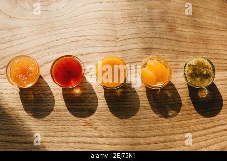 Beaucoup de confiture délicieuse multicolore dans une rangée sur une table en bois. Banque D'Images