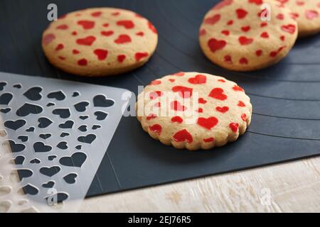 Biscuits avec un motif sous forme de coeurs, pochoir sur un tapis de cuisson Banque D'Images