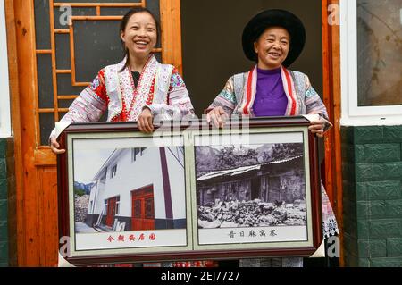 (210222) -- QIANXI, 22 février 2021 (Xinhua) -- Wang Daiyu (L) du groupe ethnique Miao et sa mère Yang Wenmei montrent des photos de leurs maisons avant et après la réinstallation au site de réinstallation des populations pauvres dans le village de Huawu, comté de Qianxi de Bijie, province de Guizhou, dans le sud-ouest de la Chine, le 20 février 2021. Situé dans la région montagneuse profonde du canton de Xinren Miao de Guizhou, le village de Huawu est célèbre pour ses paysages étonnants. Au cours des dernières années, avec les efforts du gouvernement local, le village développe la plantation, la culture et le tourisme tout en relocalisant les personnes touchées par la pauvreté. Nowa Banque D'Images