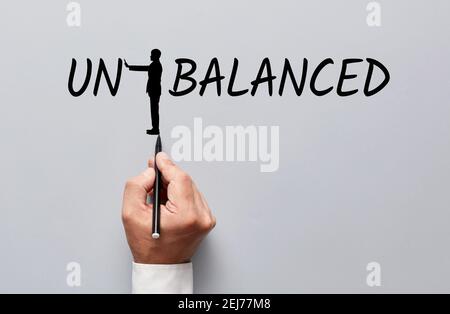 Main d'homme d'affaires dessinant une silhouette d'un homme changeant le mot déséquilibré à équilibré en poussant les lettres. Trouver le point d'équilibre dans busi Banque D'Images