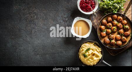 Vue de dessus de boulettes de viande suédoises kottbullar avec bols de sauce, purée de pommes de terre et canneberges sur le côté. Banque D'Images