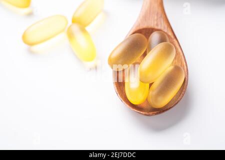 Pilules Omega 3 dans une cuillère en bois sur fond blanc. Gels à base d'huile de poisson. Gros plan - image Banque D'Images