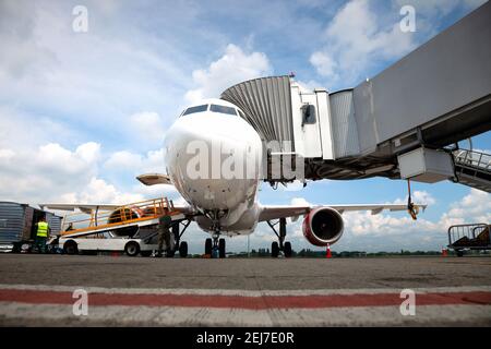 Embarquement des passagers à bord de l'avion par la passerelle d'embarquement. L'avion atterrit à l'aéroport international. Chargement des bagages. Avion blanc. Borne Banque D'Images