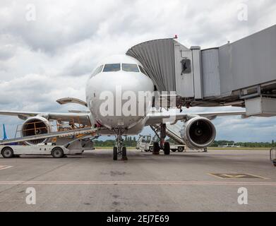 Embarquement des passagers à bord de l'avion par la passerelle d'embarquement. L'avion atterrit à l'aéroport international. Chargement des bagages. Avion blanc. Borne Banque D'Images