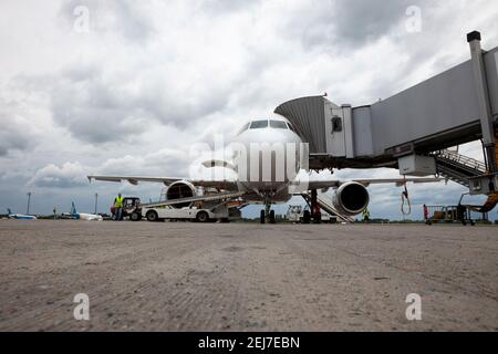Embarquement des passagers à bord de l'avion par la passerelle d'embarquement. L'avion atterrit à l'aéroport international. Chargement des bagages. Avion blanc. Borne Banque D'Images