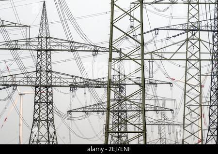 Rommerskirchen, Allemagne. 22 février 2021. Derrière une forêt de pylônes d'électricité, les éoliennes se tournent pour produire de l'électricité. Credit: Federico Gambarini/dpa/Alay Live News Banque D'Images