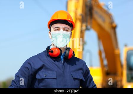 Homme masqué au travail dans un chantier de construction, concept de construction du coronavirus covid Banque D'Images