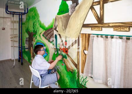 Éditorial. Un adolescent handicapé joue avec des images sur un tableau magnétique. Syndrome de Down, autisme. Centre de réadaptation, école pour spécial c Banque D'Images