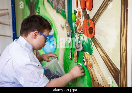 Éditorial. Un adolescent handicapé joue avec des images sur un tableau magnétique. Syndrome de Down, autisme. Centre de réadaptation, école pour spécial c Banque D'Images