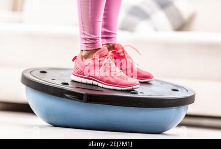 Femme en chaussures d'entraînement se tient sur un ballon d'équilibre bleu. Banque D'Images