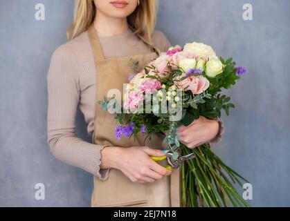 Le fleuriste coupe les tiges de fleurs dans un bouquet avec un sécateur. Les gens dans le processus de travail. Le concept d'un magasin de fleurs et de livraison de fleurs comme un Banque D'Images