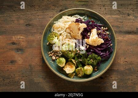 De dessus de plat appétissant avec assortiment de cabages grillés et nouilles savoureuses servies dans une assiette sur une table en bois Banque D'Images