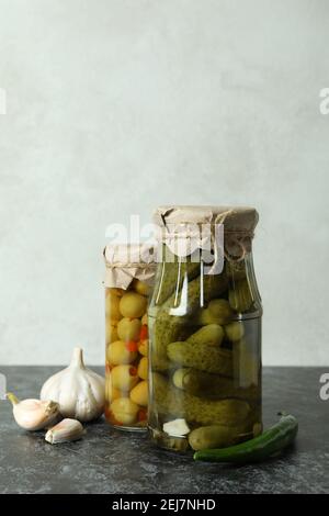 Bocaux avec concombres en conserve et olives sur table noire au smokey Banque D'Images