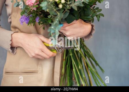 Le fleuriste coupe les tiges de fleurs dans un bouquet avec un sécateur. Les gens dans le processus de travail. Le concept d'un magasin de fleurs et de livraison de fleurs comme un Banque D'Images