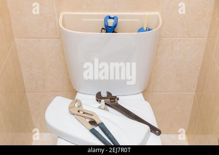 Outils de plomberie dans la toilette sur un bol de toilette blanc. Bouchon de vidange du réservoir déposé Banque D'Images