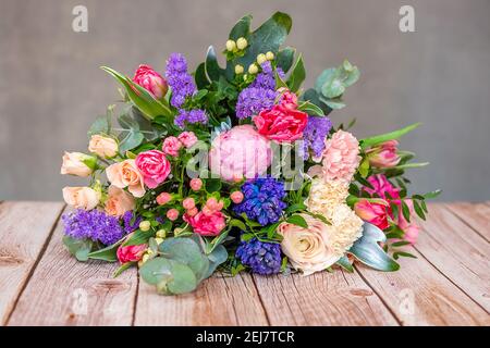 Vue rapprochée d'un beau bouquet de fleurs de coloful mélangées sur une table en bois. Le concept d'un fleuriste et de la livraison de fleurs comme une entreprise familiale, Banque D'Images