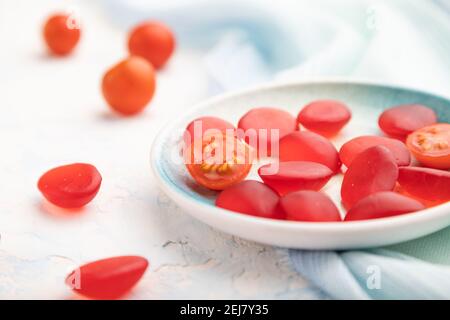 Bonbons à la tomate en gelée sur fond de béton blanc et tissu de lin bleu. Gros plan, vue latérale, mise au point sélective. Banque D'Images