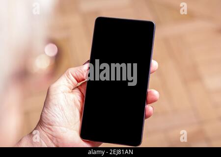 Les femmes âgées tiennent le téléphone portable à la main. Sur l'épaule. Vieille femme regardant le téléphone cellulaire. Gros plan. Écran de téléphone mobile Blank. Afficher le support. Banque D'Images