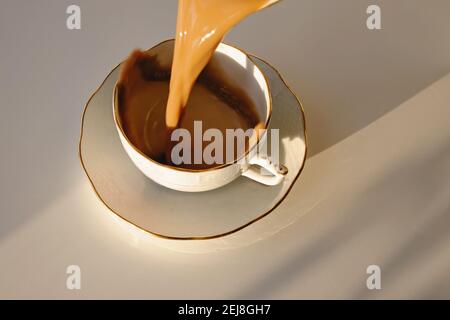 Versez un café dans une tasse rétro pour créer des éclaboussures. Banque D'Images