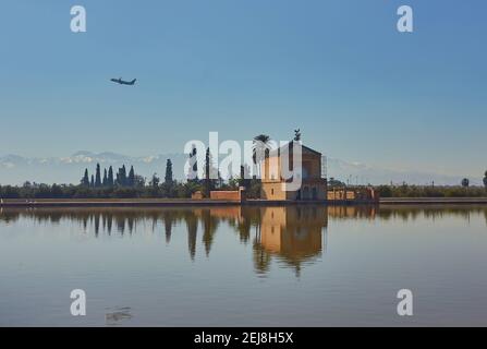 La Menara avec des montagnes de l'Atlas et un avion dans le ciel Banque D'Images