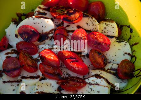 Salade traditionnelle italien Caprese avec tomates cerises et tranches de mozzarella Avec des feuilles de basilic séchées en gros plan Banque D'Images