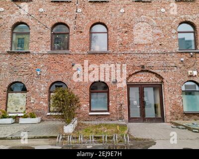 Lodz, Pologne - février 23 2020 façade de vieux bâtiment en brique rouge avec quelques buissons en face de Banque D'Images