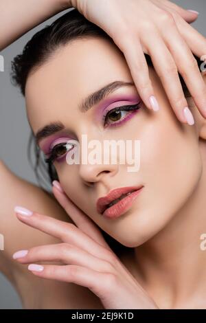 gros plan de la femme brune avec des ombres à paupières roses posant isolé sur gris Banque D'Images