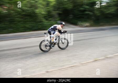 Course cyklist sur un vélo de route pendant le triathlon capturé dans le flou de mouvement. Vue de derrière. Banque D'Images