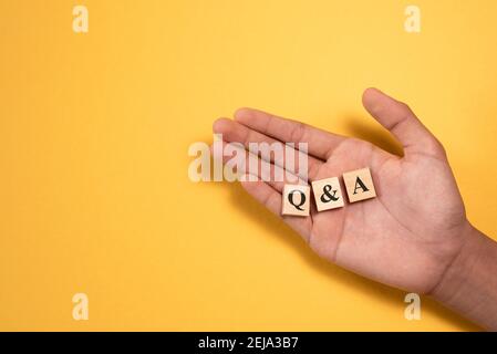 Main montrant Q et UN carreau d'alphabet en bois. Concept de questions et réponses Banque D'Images