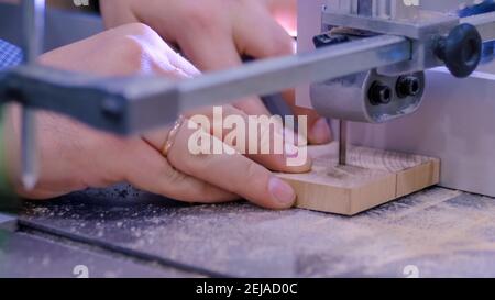Menuisier à l'aide d'une scie à ruban, coupant du bois à l'atelier - gros plan Banque D'Images